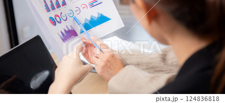 Closeup two businesswoman reviewing financial graphs and charts in modern office. Closeup two businesswoman reviewing financial graphs and charts in modern office. 124836818