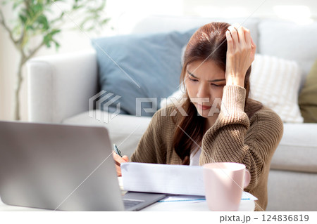 Young asian woman checking document about finance with stress and worried in living room at home. Young asian woman checking document about finance with stress and worried in living room at home. 124836819
