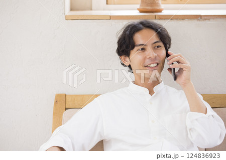ソファーに座ってスマホで会話をする若い男性 ソファーに座ってスマホで会話をする若い男性 124836923