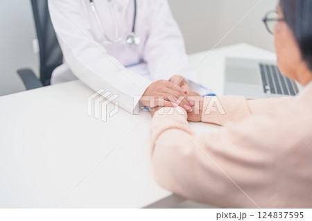 doctor holding hands with elderly female patient, showing empathy and support during a medical consultation. trust, Senior and geriatric care, healthcare, Mental Health, giving advice and emotional 124837595