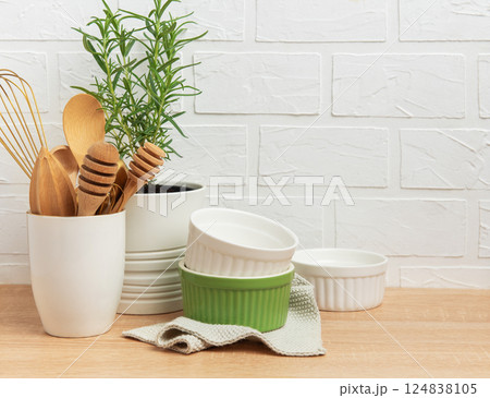 Kitchen utensils, rosemary plant, and ramekins creating a cozy culinary scene 124838105