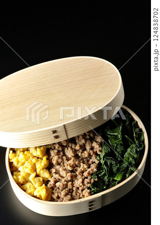 卵、肉、ほうれん草の三色弁当を黒背景で撮影 卵、肉、ほうれん草の三色弁当を黒背景で撮影 124838702