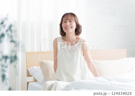 朝ベッドから起床する中高年女性 朝ベッドから起床する中高年女性 124839028