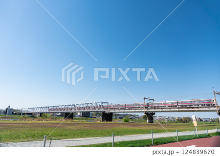 多摩川のジョギングロードから見た京王線の電車　春の青空　東京都調布市多摩川 124839670
