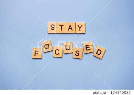 Wooden letter tiles spell out the motivational message 'Stay Focused' on a light blue background Wooden letter tiles spell out the motivational message 'Stay Focused' on a light blue background 124840087