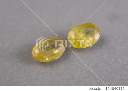 Pair of Natural Faceted Yellow Gemstones of Sphene on Gray Background 124840111