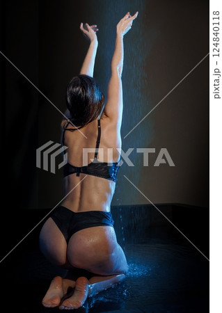 Seductive Young Woman in Black Lingerie Bathing Under Gentle Rain in Dark Setting 124840118