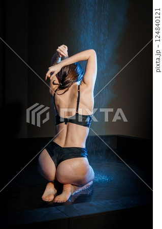 Woman in Black Lingerie Under Water Shower in Dark Studio Setting Woman in Black Lingerie Under Water Shower in Dark Studio Setting 124840121
