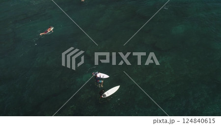 Aerial view of surfers waiting for waves in the ocean at Dreamland Beach, Bali, Indonesia, showcasing the beautiful turquoise waters and the anticipation of catching the perfect wave 124840615