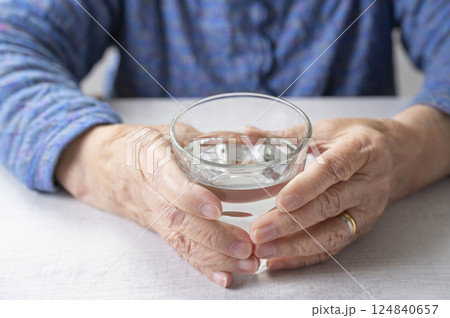 水が入ったグラスを持つおばあさんの手元 水が入ったグラスを持つおばあさんの手元 124840657