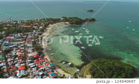Stunning aerial view of a tropical paradise showcasing the vibrant cultural landscape of Malapascua Island, Philippines, with colorful houses, traditional boats, and crystal-clear turquoise waters 124840697