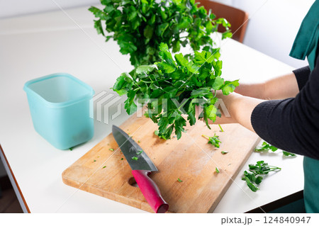 Woman preparing fresh parsley on kitchen table, home cooking and healthy food concept.Preparing parsley for winter storage 124840947
