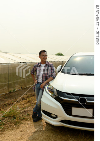 Agricultural entrepreneur standing next to his vehicle near a row of greenhouses. Success agribusiness concept 124841979