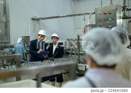 Executives in safety helmets inspecting the production line in seafood manufacturing facility 124841980