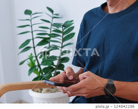 Happy young Asian man using smartphone Sitting at sofa in Living room. 124842286