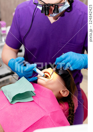 Child receiving dental care in a bright clinic with a professional dentist focused on ensuring a comfortable experience during treatment 124842425