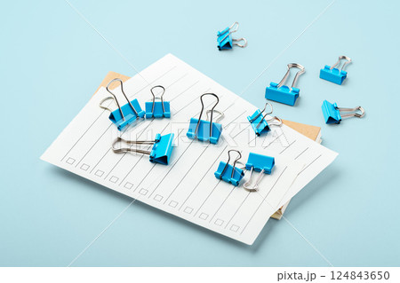 Binder clips on checklist paper on light blue background Binder clips on checklist paper on light blue background 124843650