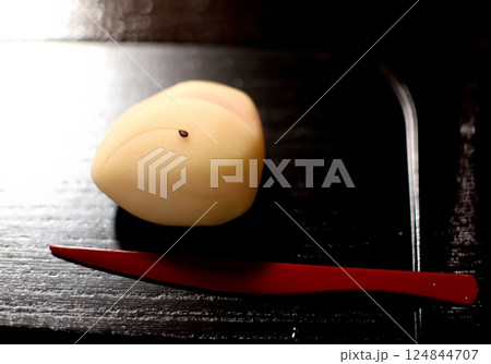 黒塗りの皿に置かれた黄身餡の和菓子と赤い楊枝 124844707