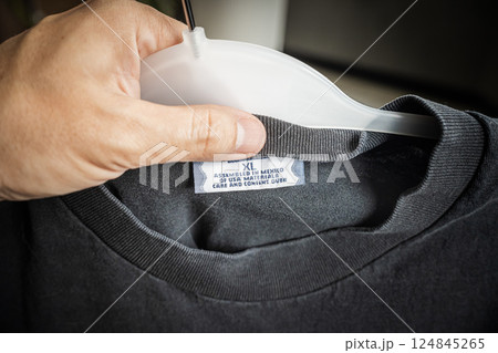 Close-up of a clothing label showing the text "Assembled in Mexico of USA materials" held by a hand, symbolizing global trade and recent tariff conflicts  124845265