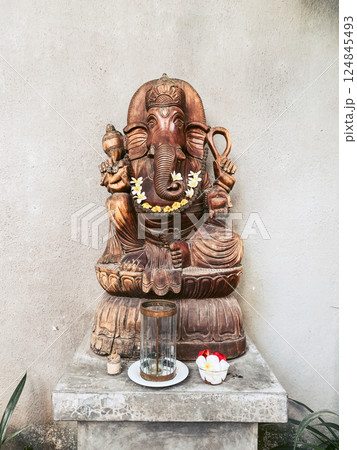 Wooden Ganesha statue with yellow flowers 124845493