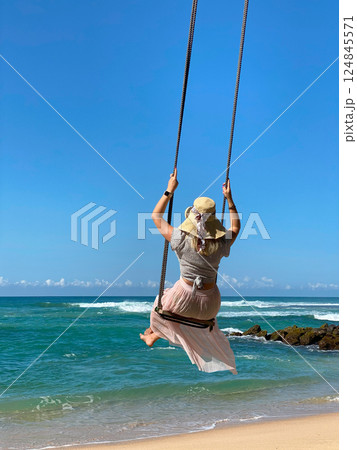 female traveller in a dress and wide-brimmed hat on a swing 124845571