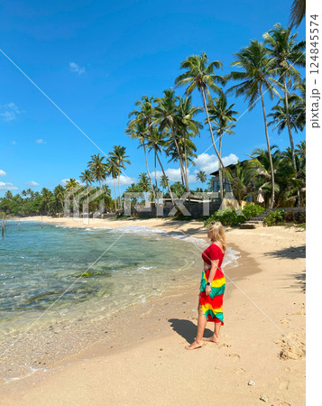 A woman walks on beach with palm trees A woman walks on beach with palm trees 124845574