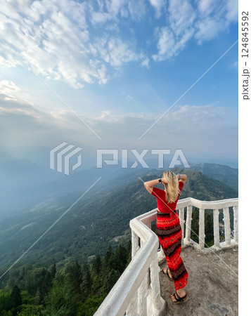 A blonde woman enjoys the view from a tower at the Ambuluwawa Temple A blonde woman enjoys the view from a tower at the Ambuluwawa Temple 124845592
