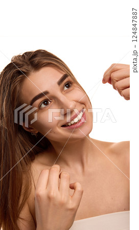 Portrait of young woman smiling, open mouth to clean teeth with white floss against white background. Oral hygiene. Portrait of young woman smiling, open mouth to clean teeth with white floss against white background. Oral hygiene. 124847887