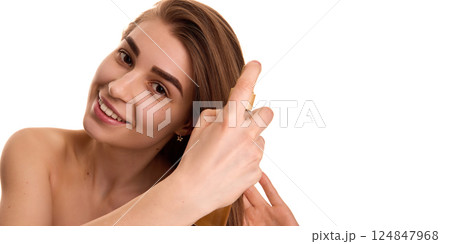 Close up of young pretty woman with long brunette hair applying spray for dry and brittle hair against white studio background. Close up of young pretty woman with long brunette hair applying spray for dry and brittle hair against white studio background. 124847968