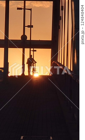 夕日に照らされながら自転車を押す少年 124848404