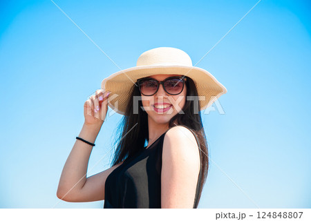 Smiling woman wearing sunhat in bright sunlight for summer fashion design. Happy summer days, travel and vacation concept Smiling woman wearing sunhat in bright sunlight for summer fashion design. Happy summer days, travel and vacation concept 124848807