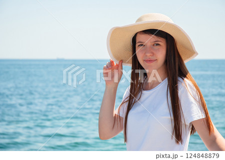 Young woman enjoying summer beach vacation with sun hat. Happy summer days, travel and vacation concept 124848879