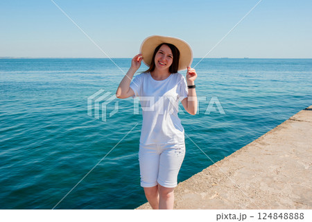 Woman enjoying a sunny day at the seaside in casual summer outfit. Happy summer days, travel and vacation concept 124848888