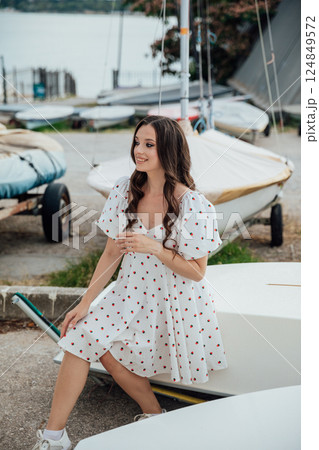 woman in summer dress sitting by sailboats in yacht club 124849572