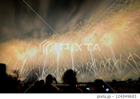 黄金のスターマインが夜空を彩る大規模花火大会と観客のシルエット 124849683