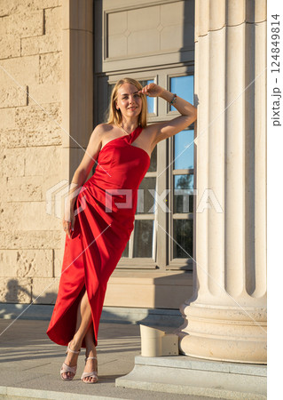 Beautiful woman in a red dress near an old building Beautiful woman in a red dress near an old building 124849814