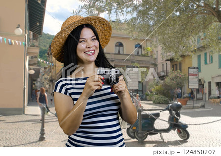 Young cheerful asian womanwith vintage photo camera standing on the street. Female tourist making a photos of sighteeing. 124850207