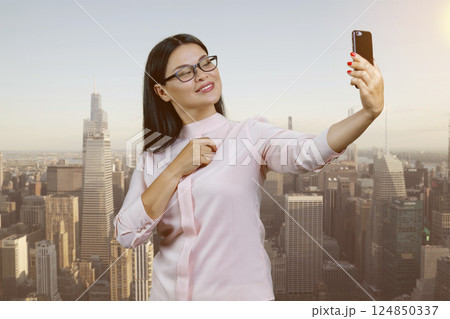 Young asian woman is making a selfie outdoors. Urban scape background. Young asian woman is making a selfie outdoors. Urban scape background. 124850337
