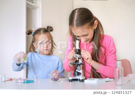 School-age children examine objects under a microscope. Scientific school research and experiments 124851327