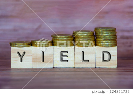 Yield text on wooden cubes with stacking golden coins. Business concept 124851725