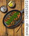 Succulent shrimps with green lemon leaves served on a sizzling platter with dipping sauce and lemon wedges 124852072