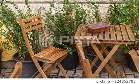 Empty bread bin street cafe without people on wooden table and chair with cutlery, raindrops 124852703