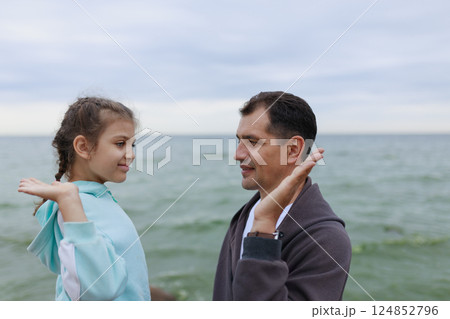Clapping palms of happy father and daughter in blur against sea Clapping palms of happy father and daughter in blur against sea 124852796