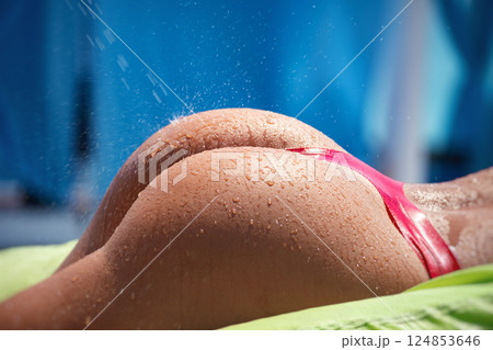 buttocks of a sporty sexy girl in close-up in splashes of water on a table buttocks of a sporty sexy girl in close-up in splashes of water on a table 124853646