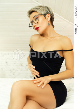 Portrait of a sexy, uninhibited LGBT girl with short hair and glasses, in a sexy black dress, emotionally echoing, demonstrating confidence on the bed in the bedroom Portrait of a sexy, uninhibited LGBT girl with short hair and glasses, in a sexy black dress, emotionally echoing, demonstrating confidence on the bed in the bedroom 124853650