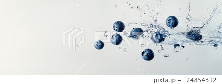 Ripe blueberries splashing into clean water create a refreshing scene against a white background, highlighting healthy eating and the natural goodness of fruit 124854312