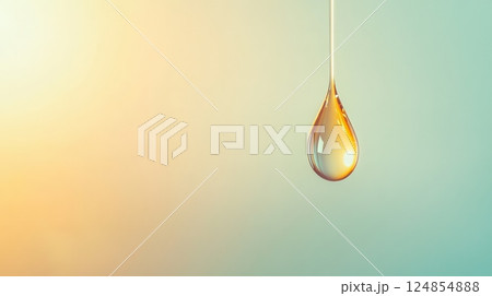 Golden translucent drop dripping against a light green and yellow background, evoking purity, freshness, and well being, ideal for cosmetics and natural products 124854888
