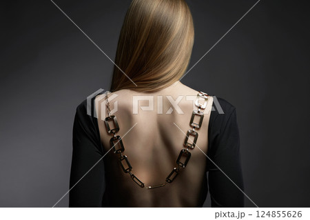 beautiful back of young woman in a black sexy dress. Girl with a necklace on her back 124855626