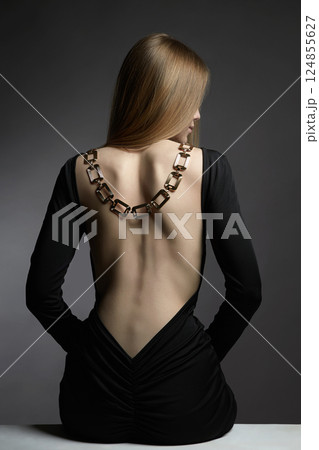 beautiful back of young woman in black sexy dress. Girl with a necklace on her back 124855627