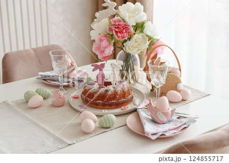Table setting with traditional easter cakes with icing decorated with gingerbread cookies in shape of rabbits on white wooden table Table setting with traditional easter cakes with icing decorated with gingerbread cookies in shape of rabbits on white wooden table 124855717
